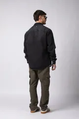 Chaqueta de jean negro desgastado, de corte recto, con cuello clásico, cierre frontal con botones y bolsillo en el pecho. Confeccionada en denim de algodón de 12 onzas.