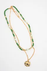 Collar doble compuesto por una cadena fina dorada con dije circular texturizado y otra tira de cuentas verdes y doradas con detalles translúcidos.