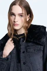 Campera de denim negro con forro de piel ecológica en el cuerpo y mangas con matelassé. Presenta doble cuello, uno de ellos desmontable, cierre frontal con botones metálicos y bolsillos tipo plaqué.