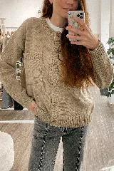 Saco tejido de lana color beige con cuello redondo, cierre frontal con botones marrones, mangas largas y dos bolsillos frontales.