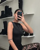 Remera sin mangas de corte ajustado, confeccionada en tela con acabado satinado, cuello redondo y largo a la cintura.