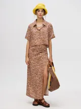 Falda larga tipo pareo con tajo lateral, confeccionada en viscosa con estampado abstracto en tonos marrones y rosados. Cuenta con tiras ajustables en la cintura.