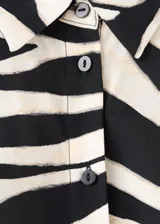 Vestido midi de viscosa con estampado de hojas en blanco y negro, sin mangas, con cuello camisero, cierre frontal de botones y cinturón a juego.