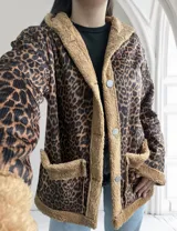 Campera de corderoy con estampado animal print, forrada con piel sintética color beige. Tiene capucha, cierre con botones a presión y bolsillos laterales.