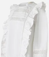 Blusa blanca de tricolina con diseño romántico, cuello redondo, mangas largas abullonadas y detalles de volados verticales en el frente. Presenta aplicaciones de encaje tipo entremedios en el pecho y en las mangas.