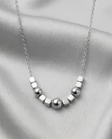Collar de cadena fina de acero con diseño central compuesto por esferas y cubos metálicos intercalados.