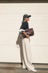 Chaqueta gris de cuello redondo y manga tres cuartos, con detalle de volantes de popelín blanco en el cuello, puños y bajo. Cierre frontal con botones.