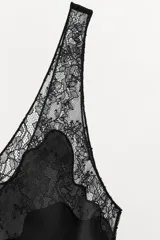 Top lencero de satén negro con aplicación de encaje transparente en el escote y los tirantes, de corte recto.