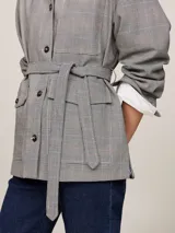 Campera tipo americana con estampado de cuadros Príncipe de Gales, cuello inglés, cierre de botones, cinturón anudable, trabillas en hombros, bolsillo de parche en el pecho y dos bolsillos delanteros tipo sobre.