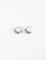 Aros tipo argolla gruesos de metal plateado, con acabado martillado o texturado irregular.