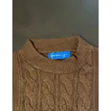 Buzo de punto color blanco con diseño de trenzas verticales, cuello redondo y mangas largas. Presenta puños y ruedo acanalados.