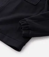 Campera pesada tipo trucker de Marfinno, confeccionada en polivelour negro. Presenta cuello camisero, cierre frontal con cremallera y dos bolsillos frontales con solapa en el pecho.