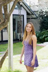 Vestido corto color fucsia con escote en V, breteles finos que se atan al cuello, corte a la altura de la cadera y falda acampanada con ruedo irregular.