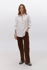 Camisa de lino color beige, de manga larga, con cuello clásico y botones marrones.