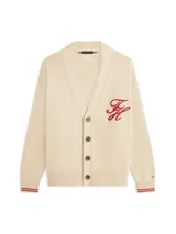 Cárdigan de punto grueso en color beige, con cuello en V, cierre frontal con botones y bolsillos de ojal. Presenta puños y bajo acanalados con líneas rojas y blancas, y un logo script bordado en rojo en el pecho.