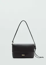 Bolso de hombro pequeño en color negro, con diseño estructurado y cierre de solapa con botón joya metálico. Presenta un asa larga con nudo ajustable en uno de los laterales.