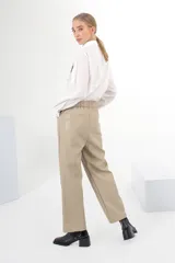 Pantalón de vestir color beige, de corte recto, con bolsillos laterales y traseros. Se ajusta a la cintura con cinturón de cuero marrón.