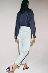 Jeans de tiro alto y silueta tapered, confeccionados en denim negro con costuras en tono contrastante. Cuenta con diseño de cinco bolsillos, trabillas para cinto y cierre frontal con cremallera y botón metálico.