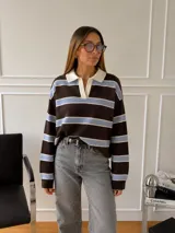 Sweater de punto con diseño a rayas horizontales en tonos marrón, celeste y blanco. Presenta cuello polo con solapas en color crema, manga larga y corte holgado.