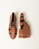 Zapato acordonado de cuero vacuno color marrón con aberturas laterales y cordones negros.