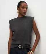 Chaleco de punto negro con cuello redondo, hombreras estructuradas y diseño sin mangas. Confeccionado en tejido de punto con acabado acanalado en el ruedo.