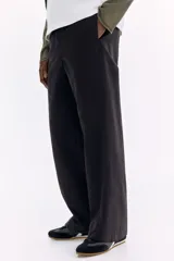 Pantalón en mezcla de algodón color negro, con cintura elástica con cordón de ajuste y botón. Presenta bolsillos laterales discretos y costuras giradas en las piernas, con un corte relajado.