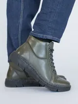 Botín de cuero color verde oscuro con sistema de ajuste mediante cordones negros y suela de poliuretano flexible. Presenta una caña de 10 cm y un taco de 3 cm, ofreciendo un diseño ergonómico y confortable para el uso diario.