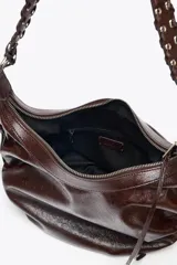 Bolso de hombro marrón oscuro con efecto craquelado, asa con detalles de flecos y anillas metálicas. Incluye bolsillo interior con cierre de cremallera.