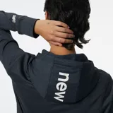 Canguro New Balance de dama, modelo Relentless Terry, color gris oscuro jaspeado. Confeccionado en tejido de rizo con tecnología NB DRY de secado rápido. Presenta capucha con cordón, mangas largas y banda diagonal en el pecho con el logo de la marca.