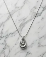 Collar de acero con cadena tipo serpiente y dije colgante en forma de lágrima con diseño de capas concéntricas.