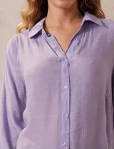 Camisa larga de rayón, con cuello clásico, cierre frontal con botones y mangas regulables con presilla. Presenta un diseño holgado con tajos laterales en el ruedo.