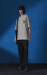 Remera de manga corta y cuello redondo con calce oversize, color beige con estampa gráfica en negro que incluye texto y un rostro femenino estilizado con llamas.