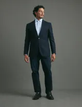 Saco de vestir azul oscuro con textura sutil, corte entallado, cierre frontal de un botón y solapas clásicas.