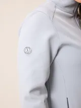 Campera softshell blanca con cierre frontal completo, cuello alto y bolsillos laterales. Presenta un bolsillo vertical con cierre en el pecho y el logo de la marca bordado.