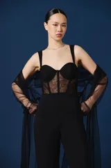 Mono largo negro con diseño tipo corset en el torso, con copas estructuradas y paneles de encaje semitransparente. Presenta breteles anchos y se complementa con una estola de tul negro incorporada.