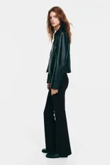 Pantalón de tiro alto confeccionado en punto roma, con diseño ajustado en la parte superior y piernas acampanadas. Presenta bolsillos insertados decorativos en la parte frontal.