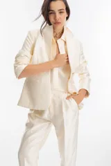 Blazer color crema confeccionado en tafeta, con cierre de un botón y mangas largas.
