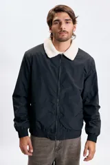 Campera tipo bomber color negro con cuello de corderito en color crema, cierre frontal y puños elásticos.