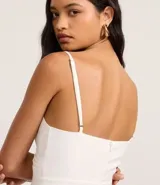 Mono blanco de pantalón ancho (pantalona) con escote cruzado en V y breteles finos ajustables.