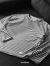 Buzo de tela fina, liviano y cómodo, con estampado de rayas horizontales blancas y negras, cuello redondo y puños acanalados.