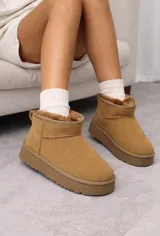 Botas tipo pantubota color camel, confeccionadas en material gamuzado con interior de piel sintética y suela de plataforma plana.