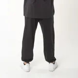 Pantalón de jogging negro de corte oversize, confeccionado en algodón con felpa interior. Presenta bordado con la frase 'JUST BEGIN' en la parte inferior de la pierna derecha y detalle bordado en la pierna izquierda.
