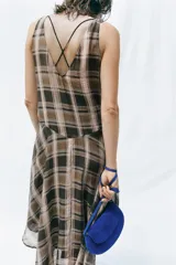 Vestido midi de escote en V y tirantes anchos, con bajo asimétrico y estampado de cuadros en tonos marrones, negros y beige.