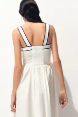 Vestido midi de algodón color blanco, con escote corazón, breteles anchos y espalda con punto smock. Presenta cuerpo entallado, costura fruncida en la cintura y pollera con vuelo, con ribetes negros en contraste en el escote y el bajo.