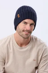 Gorro tejido de punto grueso con diseño acanalado y vuelta en el borde. Incluye una pequeña etiqueta de cuero sintético en el lateral.