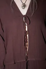 Camisa de manga larga color crema o beige claro, con textura arrugada, cuello camisero y cierre frontal mediante lazos anudados.