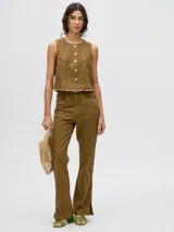 Pantalón de denim color marrón, de tiro alto y calce ochentoso con terminación estilo oxford. Cuenta con apliques metálicos decorativos alrededor de los bolsillos y a lo largo de las costuras exteriores.