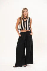 Pantalón negro de pierna súper amplia, confeccionado en denim fino y liviano con caída fluida. Tiene cintura elastizada con lazo regulable, bolsillos laterales y pinzas en la delantera.
