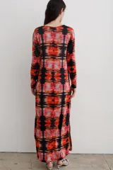Vestido largo de corte recto con escote en V y mangas largas. Presenta un estampado abstracto en tonos rojos, naranjas y negros, con tajos laterales en el ruedo.