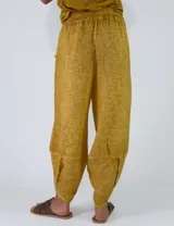 Pantalón de lino color amarillo mostaza, de corte bombacho y relajado, con bolsillos delanteros aplicados y cintura elástica.